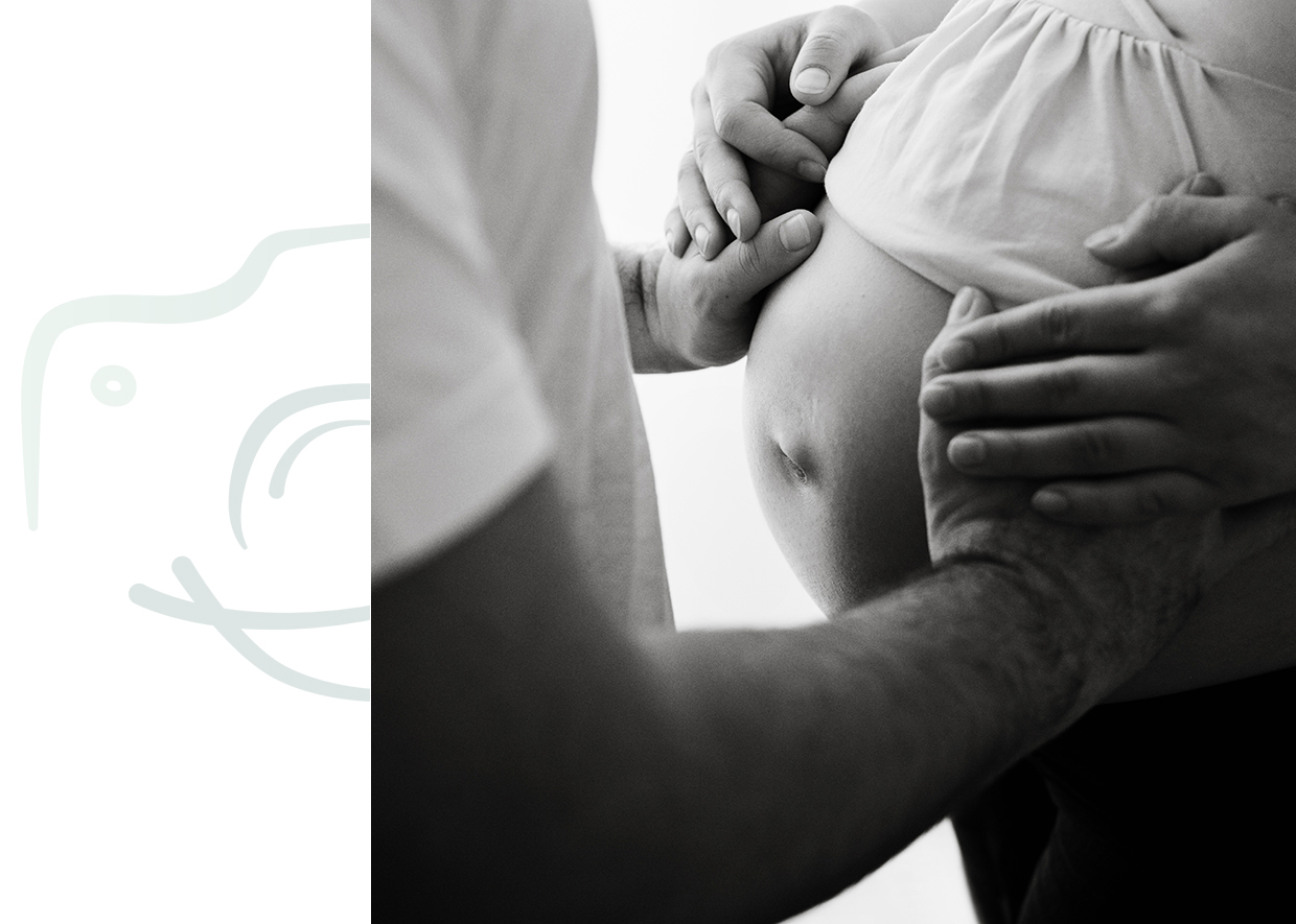 Glücklicher werdender Vater legt seine Hände auf den Babybauch im Rahmen eines Babybauch-Shootings in Rostock