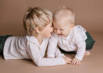 Ein Baby und ein Kleinkind spielen und lachen auf dem Boden im Fotostudio beim Kinder-Fotoshooting in Rostock
