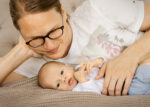 Glückliche Mutter mit ihrem neugeborenen Baby beim Baby-Fotoshooting - Familienfotos Rostock und Umgebung by Jenny Schuster